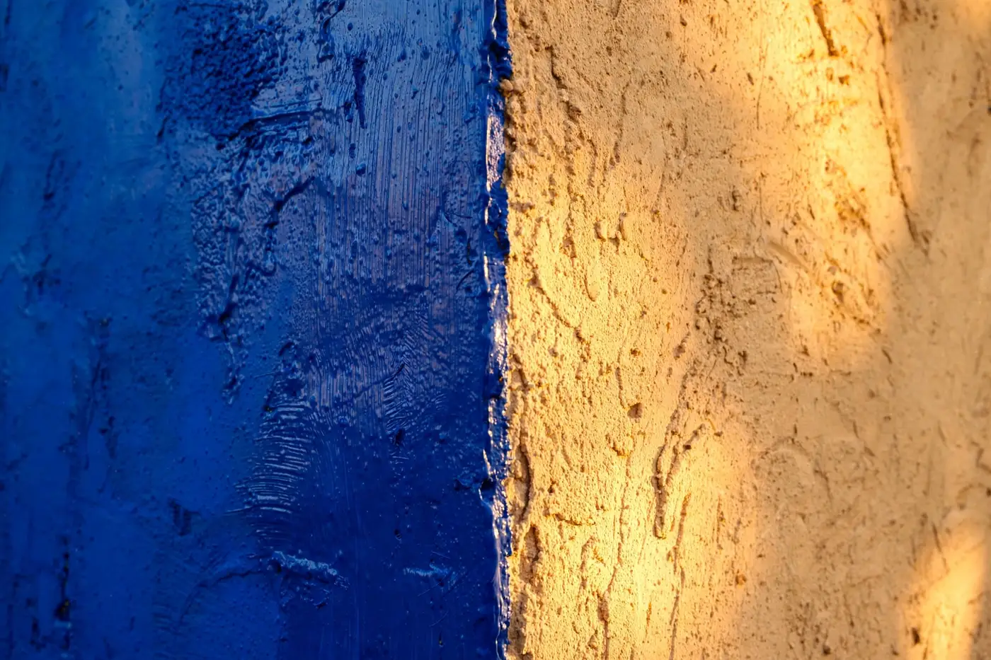 Fresh ultramarine paint meeting a sunlit plaster wall, a clean wet edge
